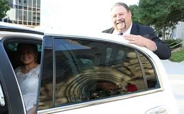Bride waving from the window of a Cynthia's limousine