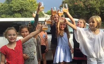 Group celebrating with a toast beside their limousine