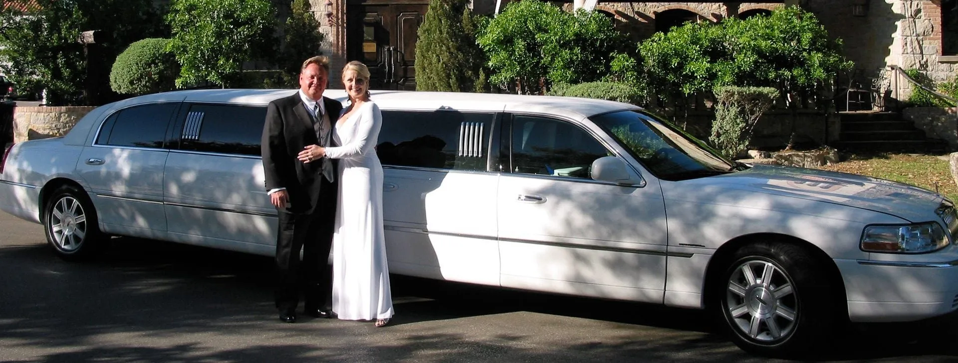 Bride and groom beside a white stretch limousine at an Austin wedding